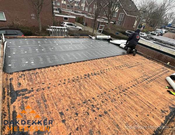 Dakdekker legt onderlaag op plat dak met houten constructie in Meerssen