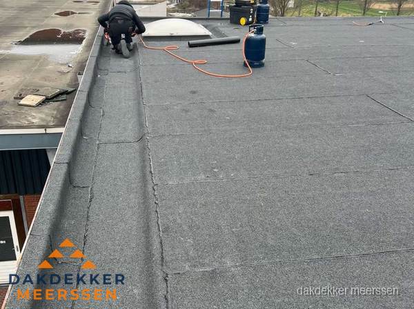Dakdekker repareert bitumen dakbedekking op groot plat dak in Meerssen Dakdekker repareert bitumen dakbedekking op groot plat dak in Meerssen