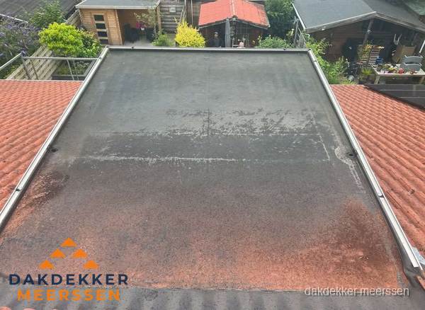 Verouderd plat dak met slijtage tussen schuine daken in Meerssen Verouderd plat dak met slijtage tussen schuine daken in Meerssen