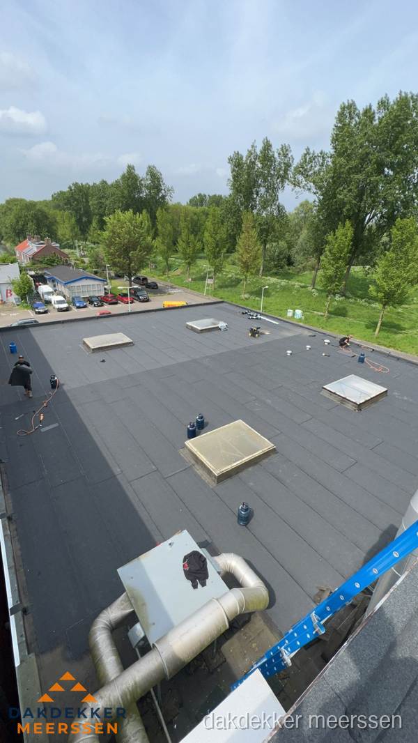 Dakdekker aan het werk op groot plat dak met bitumen in Meerssen