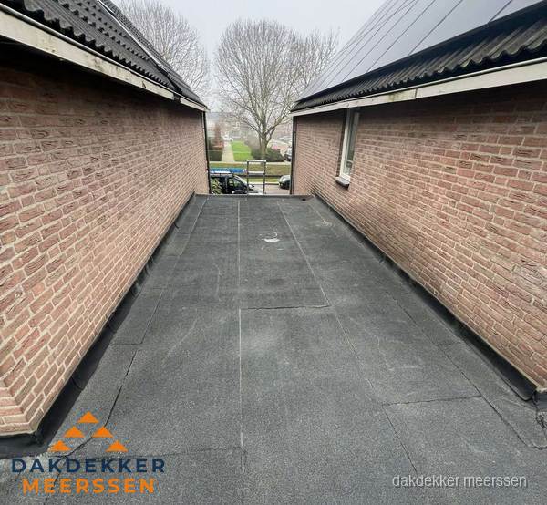 Plat dak met bitumen dakbedekking tussen bakstenen muren in Meerssen Plat dak met bitumen dakbedekking tussen bakstenen muren in Meerssen